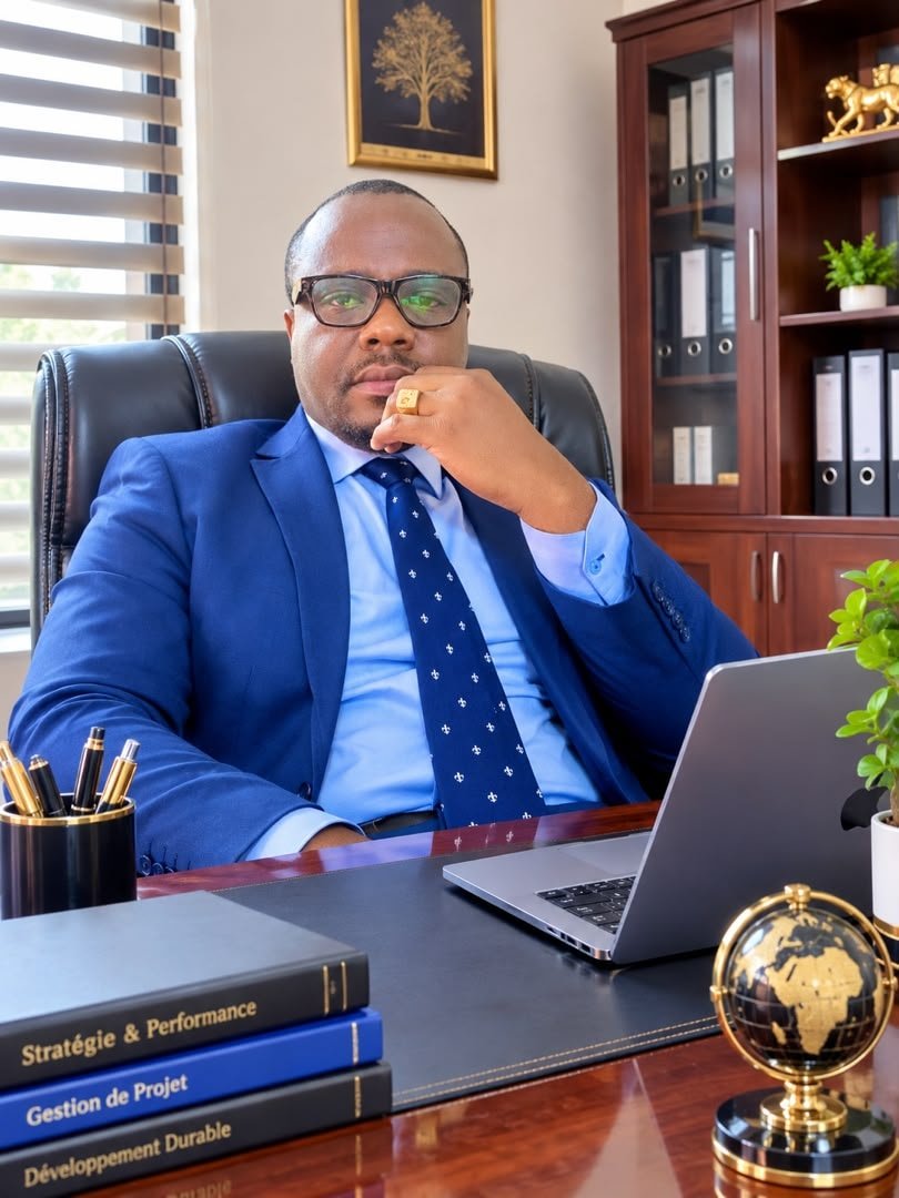 Claude Jess Rodney MOUTSILA, Managing Director of ESPOIR.SARLU, in a blue suit, seated at a desk.